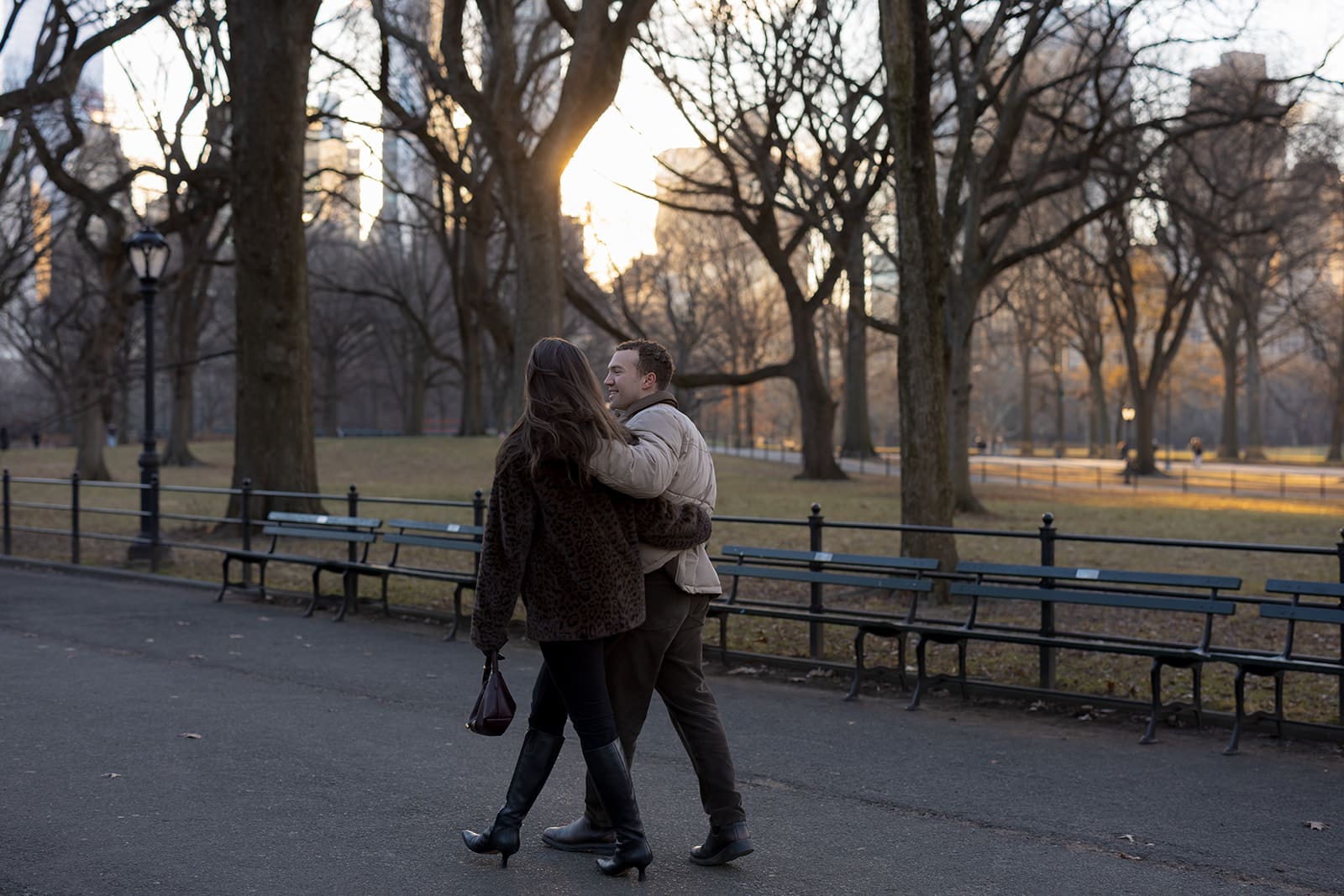 Carlie and Mat walking hand in hand along a Central Park path in winter
