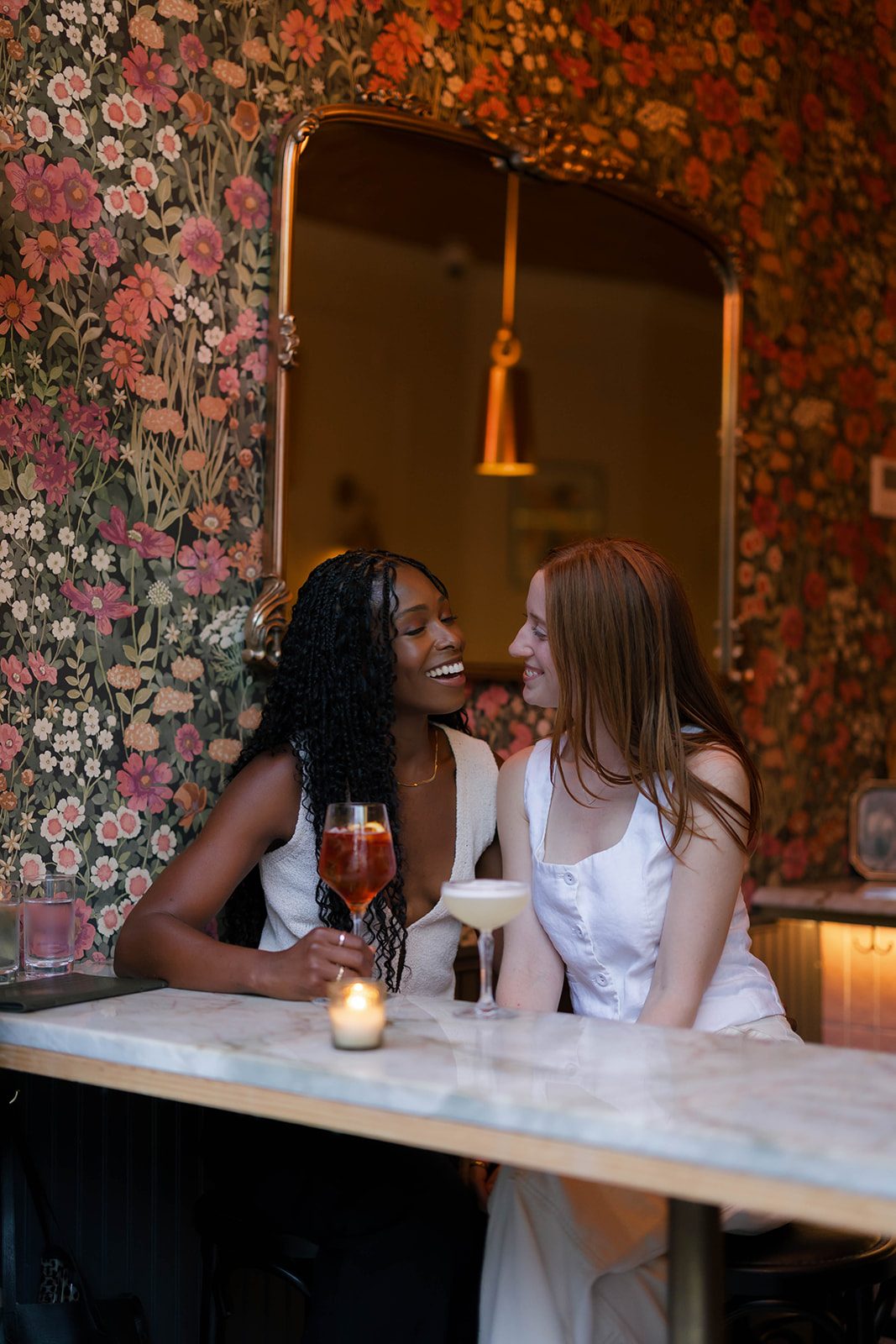 Cassia and Laura laughing together at a table inside Bar Louise