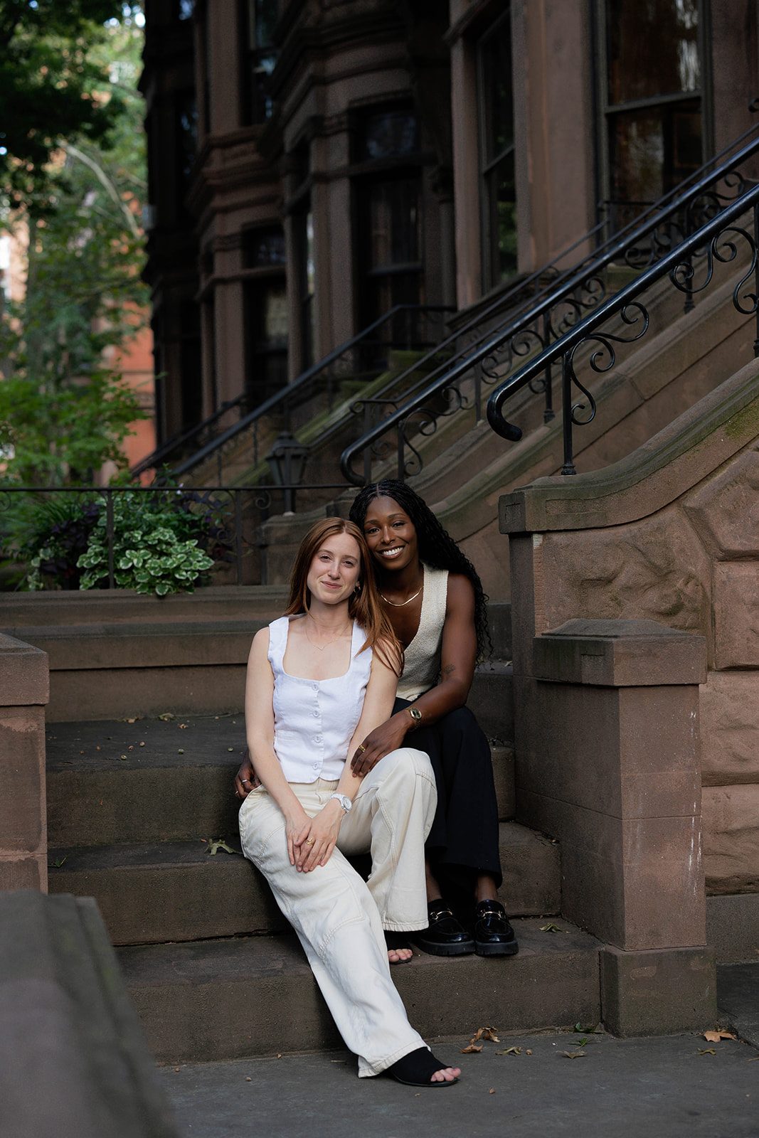 Cassia and Laura sitting together on a Park Slope brownstone stoop
