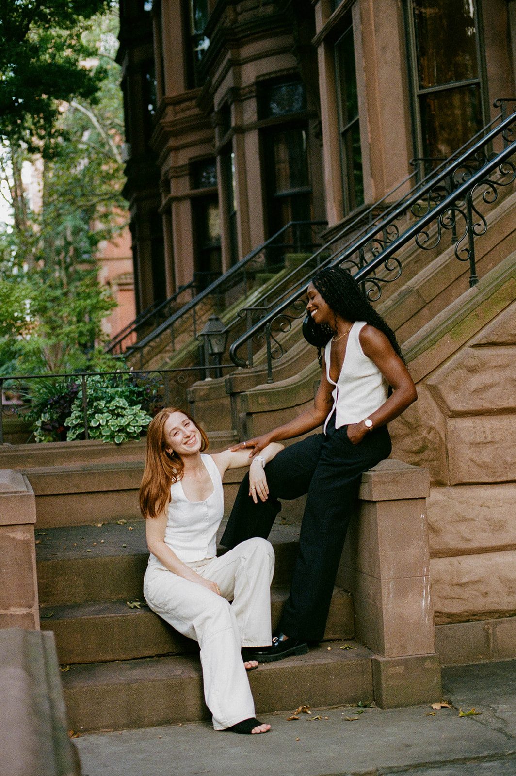 Cassia and Laura sitting on a brownstone stoop in Park Slope photographed on 35mm film