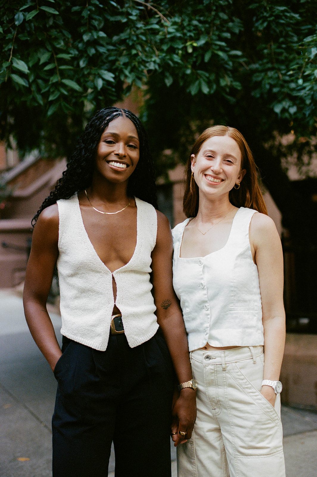 Cassia and Laura smiling together on a Park Slope sidewalk photographed on film