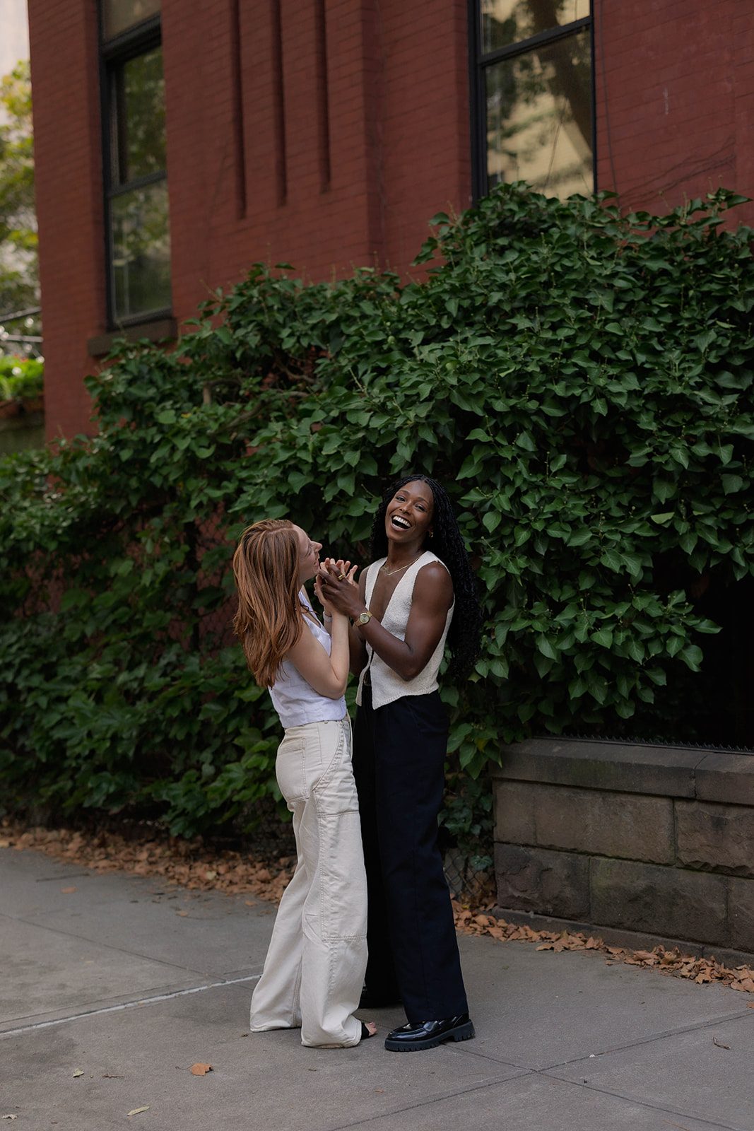 Cassia and Laura hugging beside a lush green wall in Park Slope