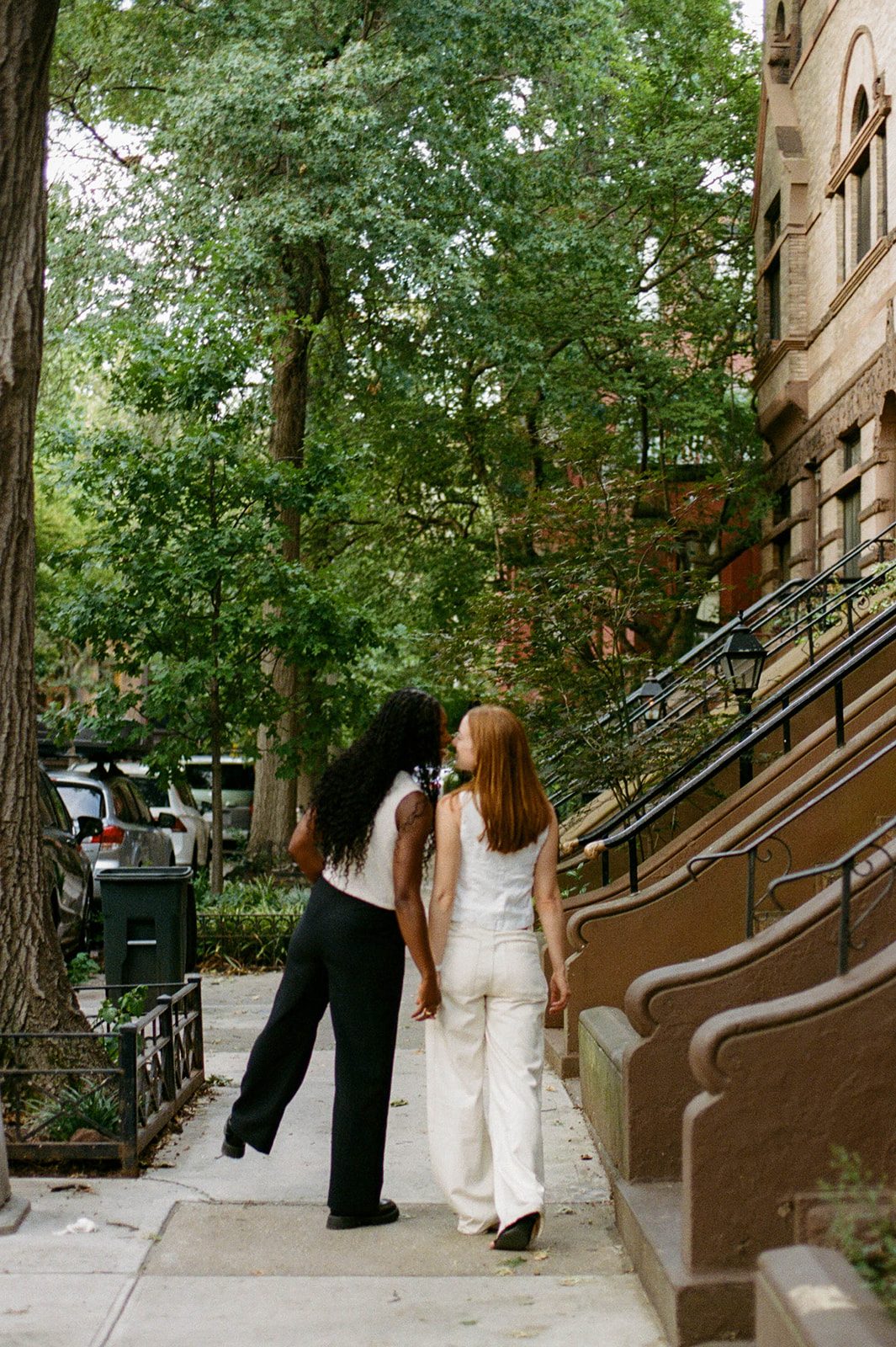Cassia and Laura walking past brownstone stoops in Park Slope on 35mm film