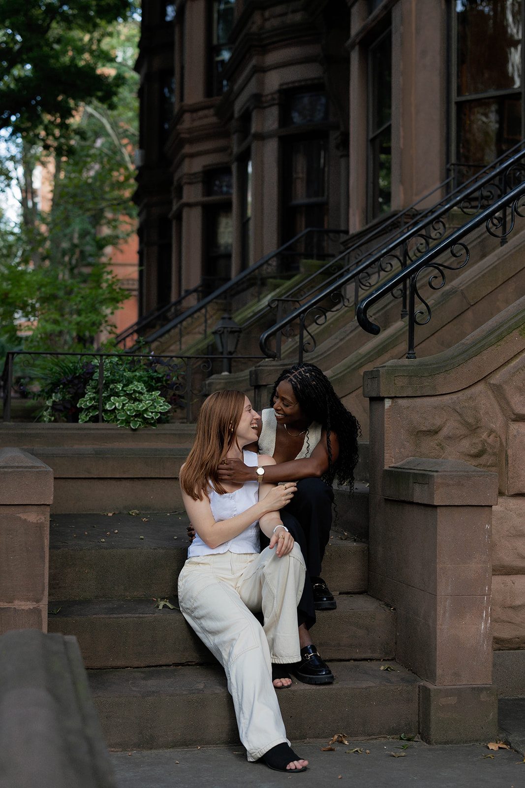 Cassia and Laura smiling together on the steps of a Park Slope brownstone