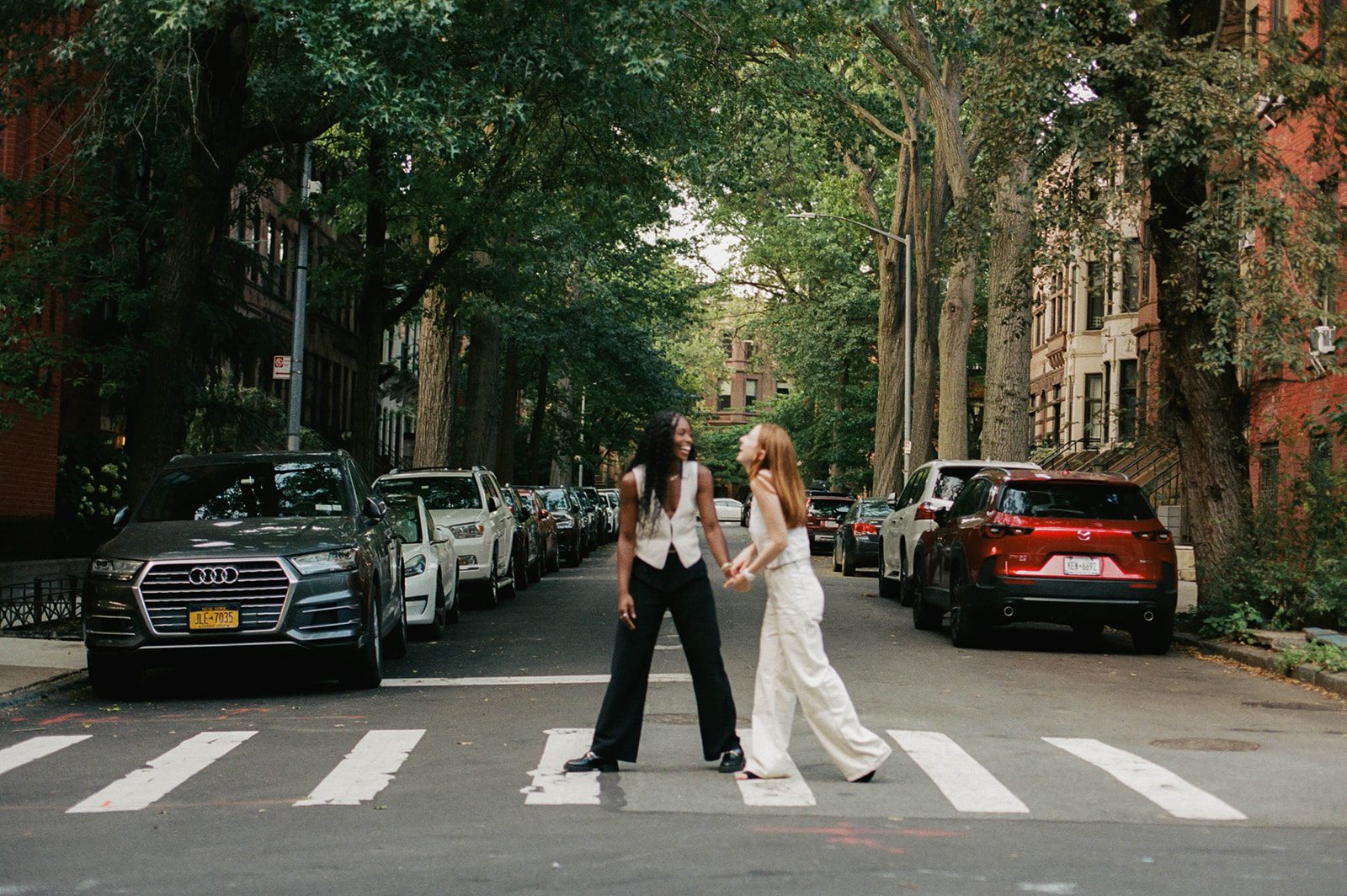 Cassia and Laura holding hands in a Park Slope crosswalk, photographed on 35mm film