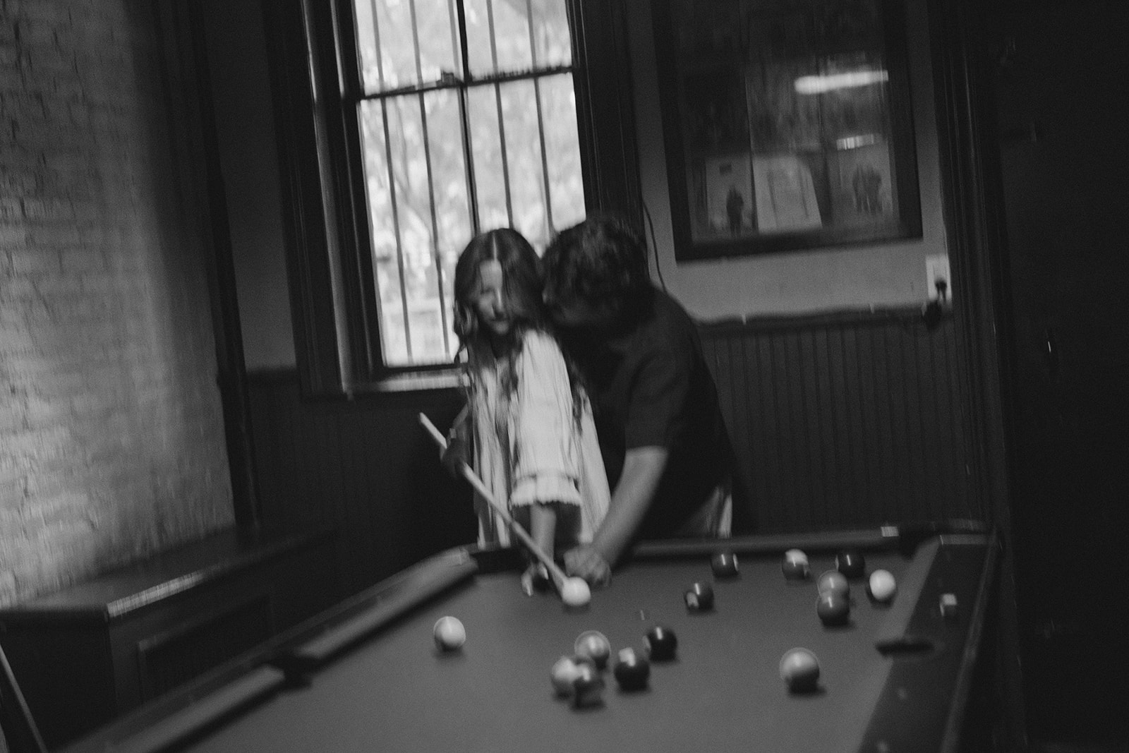 Motion-filled black-and-white photograph of Sadie and David playing pool