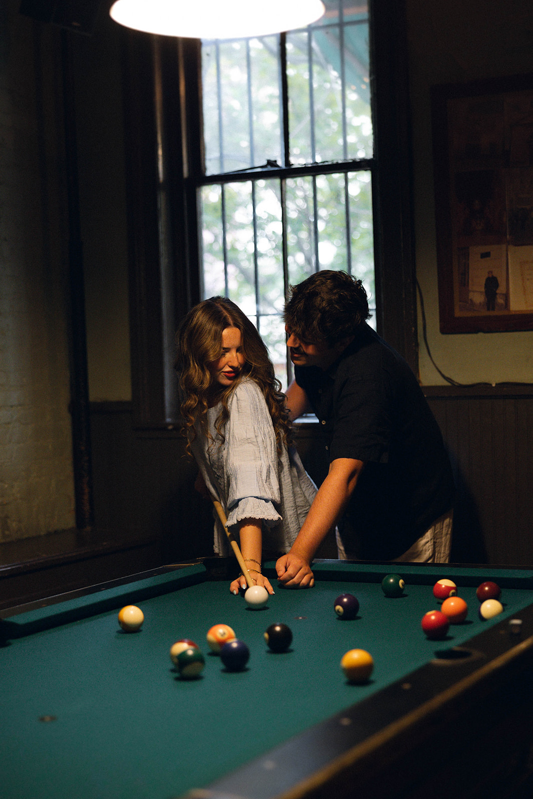 Sadie taking a pool shot while David leans beside her at Brooklyn Social