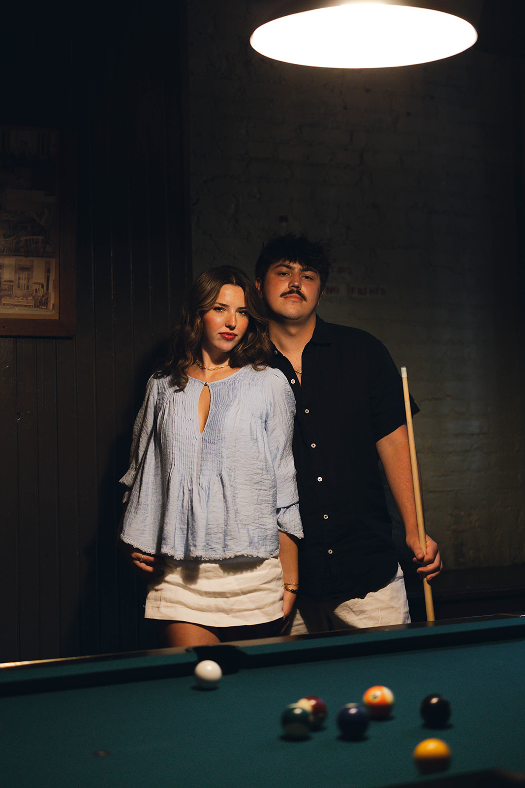 Sadie and David standing beneath the billiard lamp at Brooklyn Social